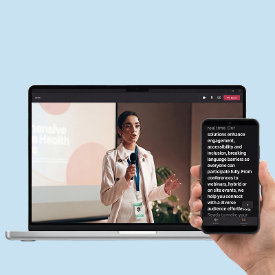 A laptop showing a live presentation beside a phone displaying captions of the speaker in another language