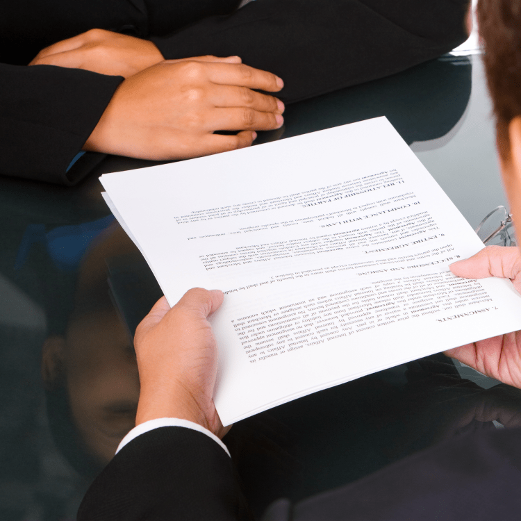 Two professionals reviewing a printed contract across a conference table
