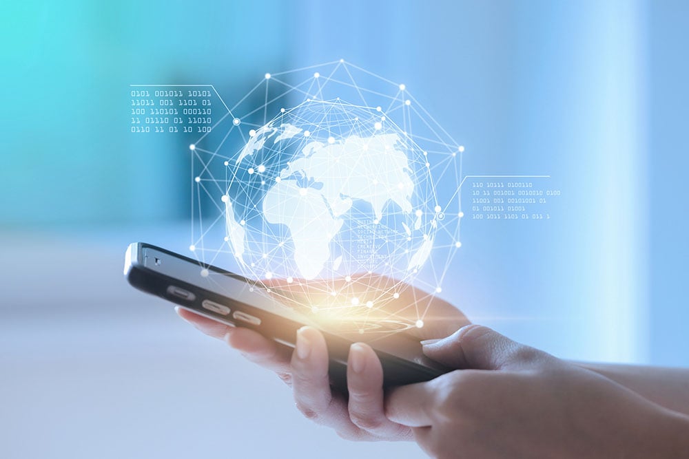 a hand holding a phone with globe hologram