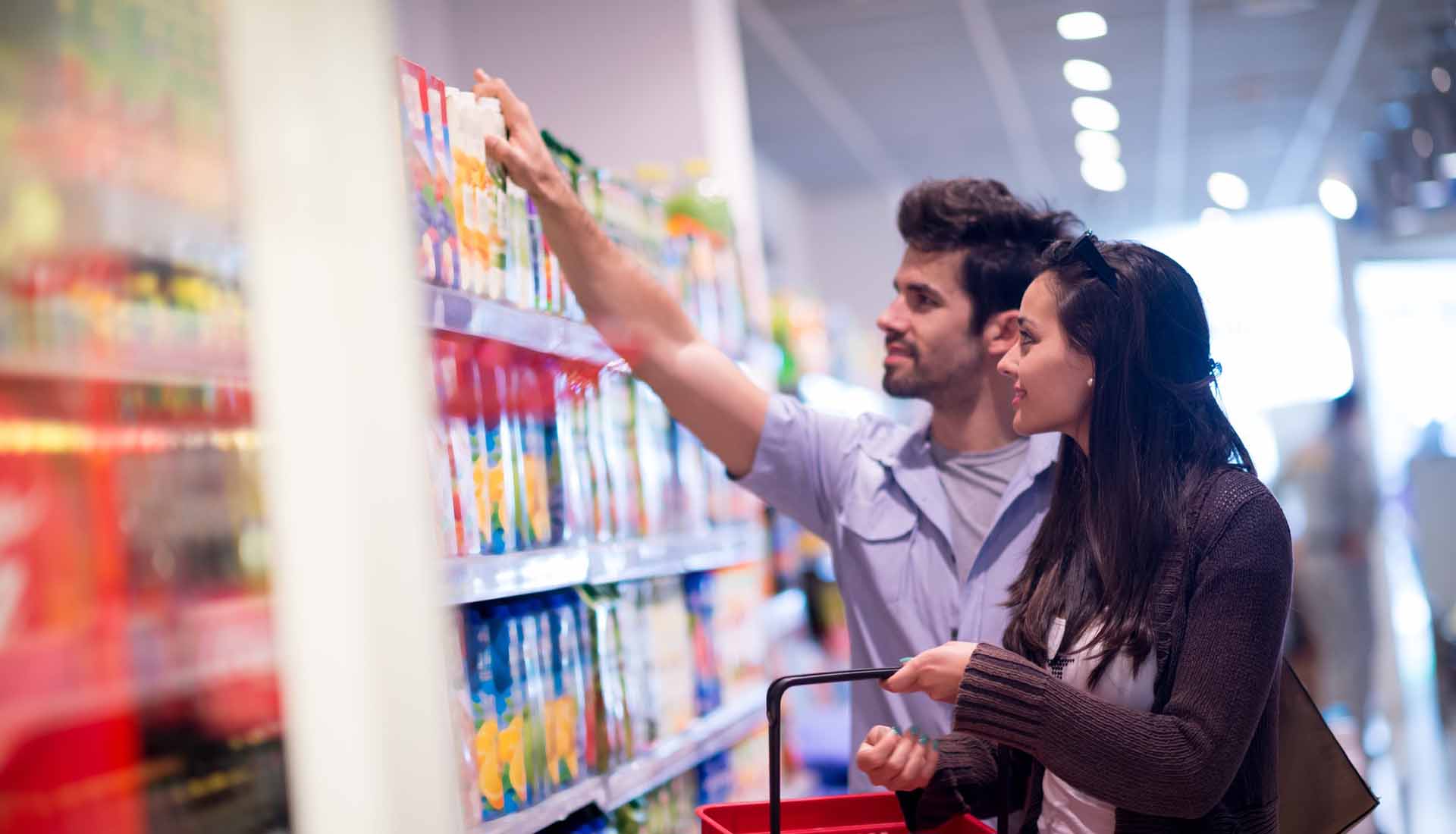 Two shoppers reach for a packaged product on a store shelf