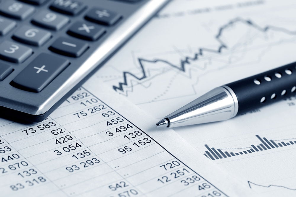 Calculator, pen, and financial charts on a desk