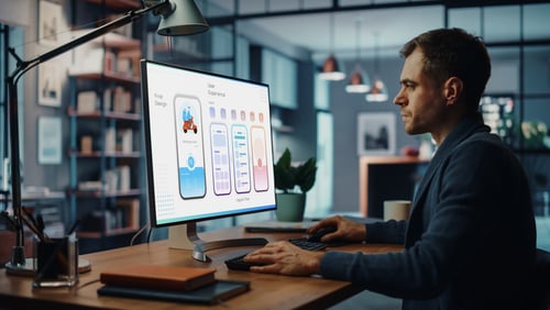 Developer reviewing app interface designs on a desktop computer