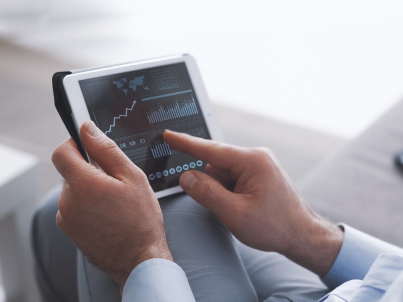 Hands holding a tablet showing sales analytics charts