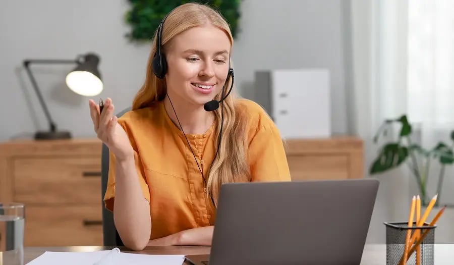 Interpreter wearing a headset smiling at a laptop in an office