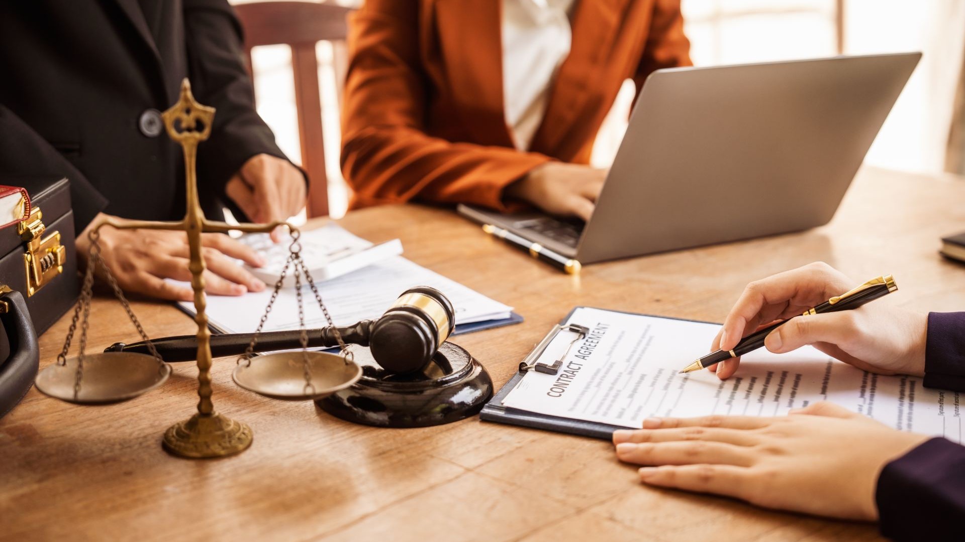 Attorney and client reviewing a contract at a desk with a gavel and scales of justice
