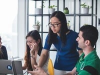 Group of colleagues collaborating around a laptop during a meeting.