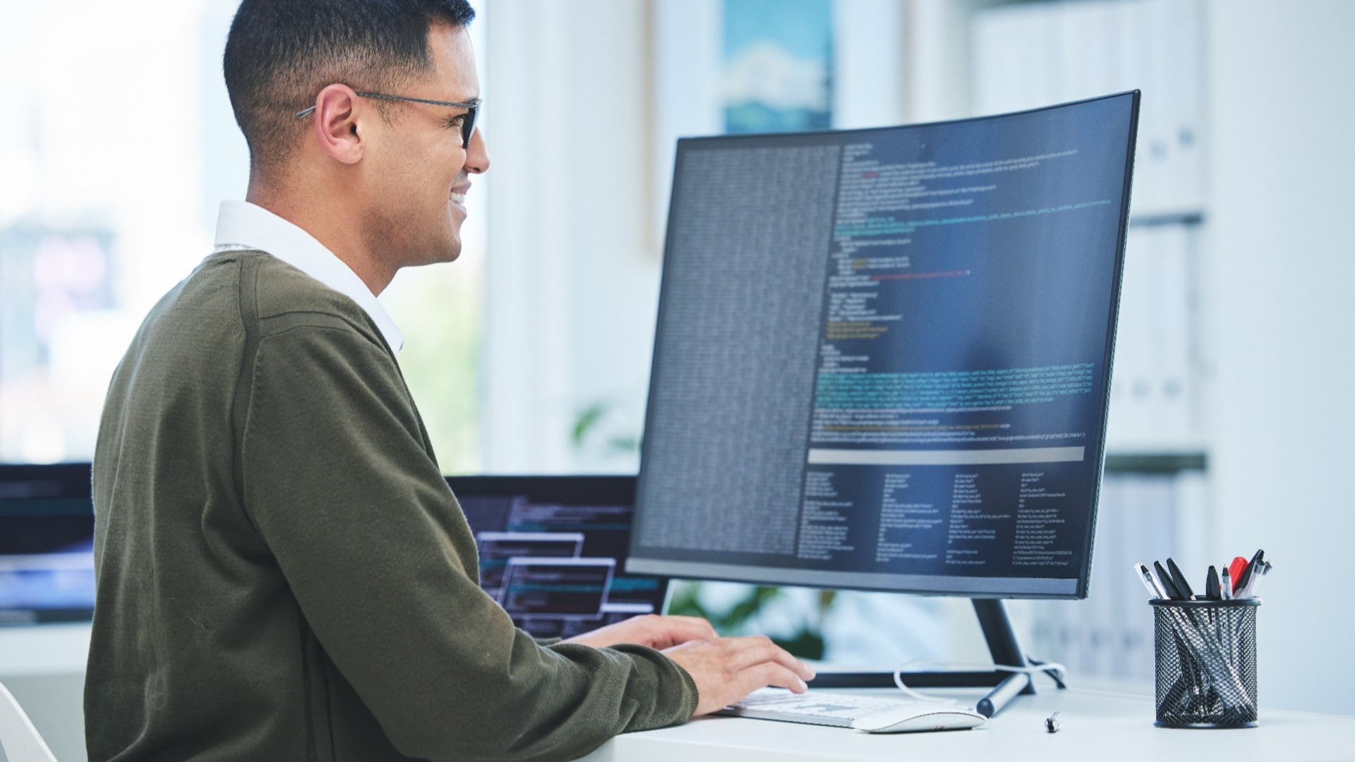 Developer reviewing code on a curved monitor