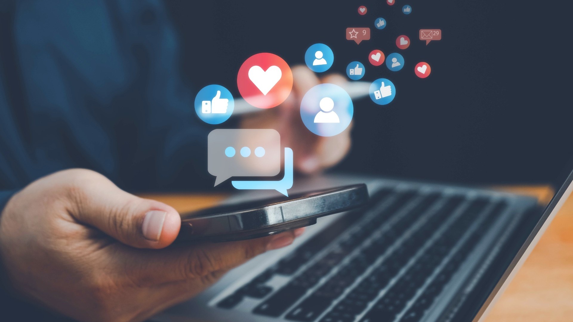 Hand holding a smartphone with social-media reaction icons rising from the screen