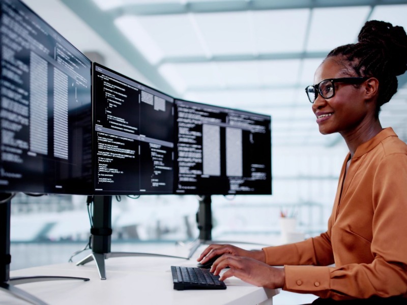 Developer coding at a multi-monitor workstation