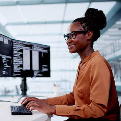 Developer writing code at a two-monitor workstation