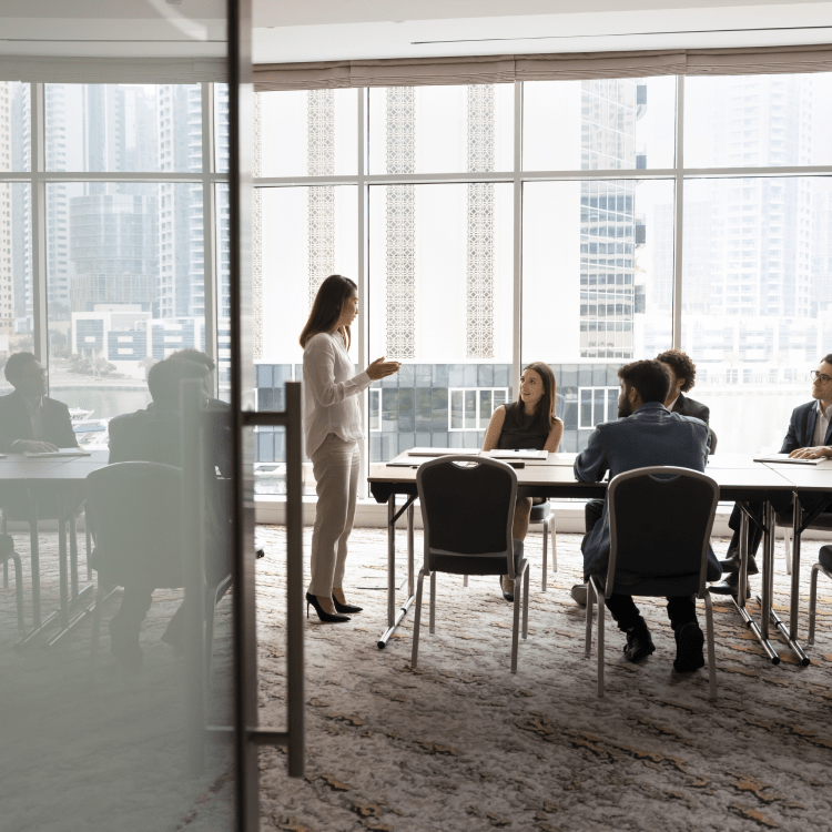 Employees seated around a conference table listening to a colleague present