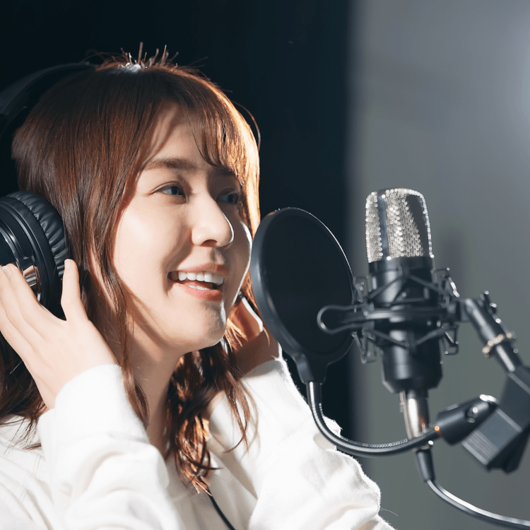 Voice actor in headphones recording in front of a studio microphone and pop filter