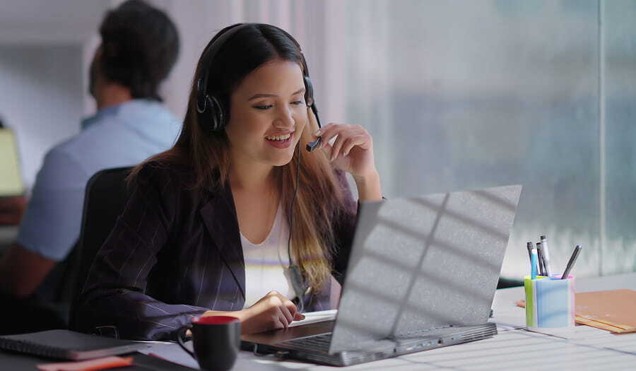 Professional interpreter wearing headset while working on laptop in office setting.