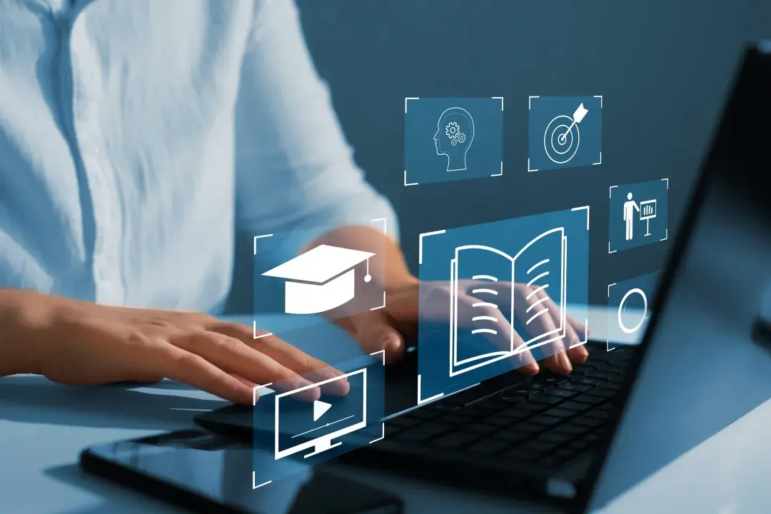 Hands typing on a laptop with floating digital learning icons