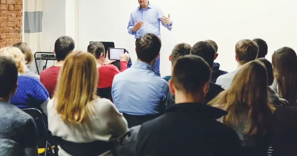 A speaker presenting to a seated audience at a community event