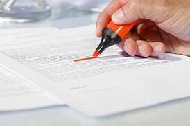A hand marking a line on a printed document with an orange highlighter