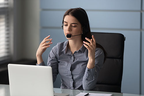 Woman sits at desk with headset