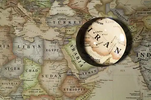 magnifying glass focusing on the country of Iran on an map. 
