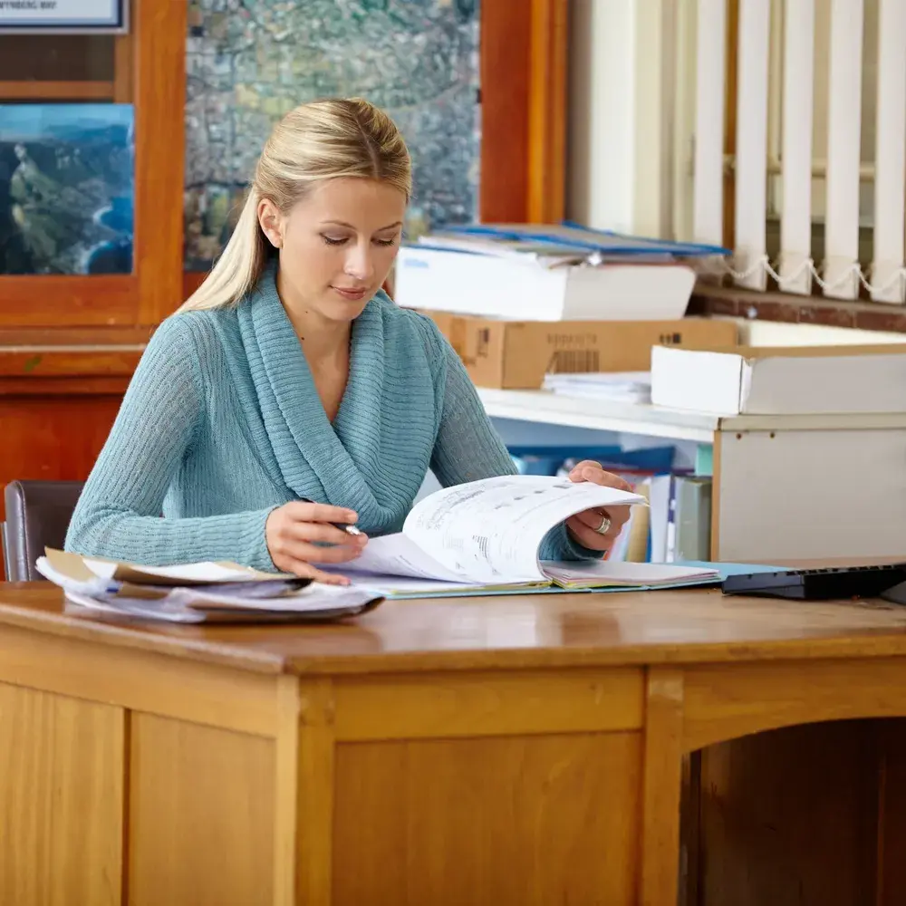 School administrator reviewing printed documents at a desk
